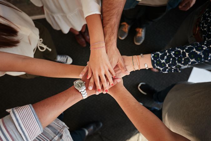 Top view of group of people stacking hands together