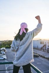 Woman in pink scarf raising fist against breast cancer