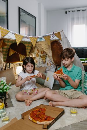 Children eating pizza and lemonade while camping at home