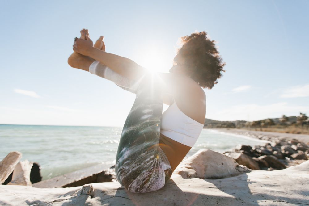 Sportive woman performing yoga posture on stones in nature