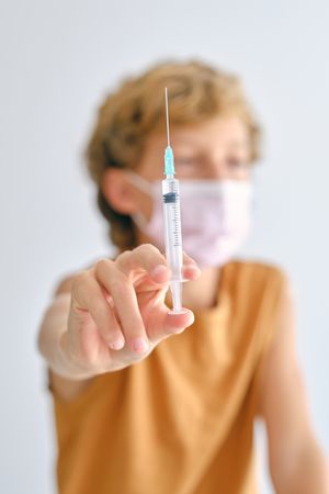 Boy in mask with vaccine in syringe