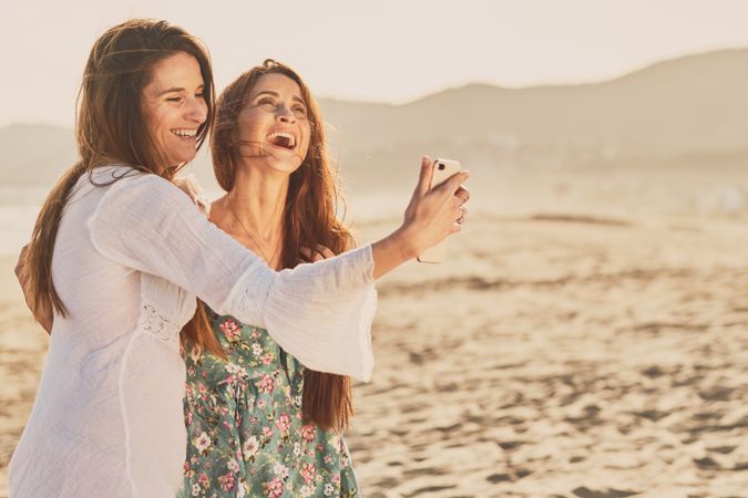 Smiling women making selfie on beach
