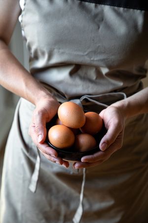 Faceless person holding bowl with eggs