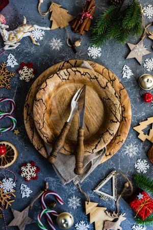 Rustic table setting surrounded by Christmas decorations, candy canes and fir scattered on marble table