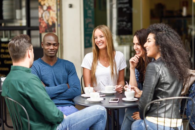 Multiracial group of five friends having a coffee and talking