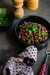 Traditional Georgian lobio dish with green onions on wooden table with dotted kitchen towel