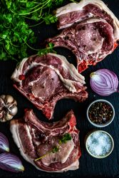 Top view of raw pork steaks with herbs, garlic, onion, salt and pepper 