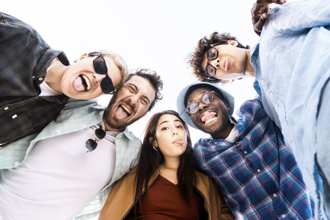 Funny diverse group of young friends making silly faces outdoors in the sun