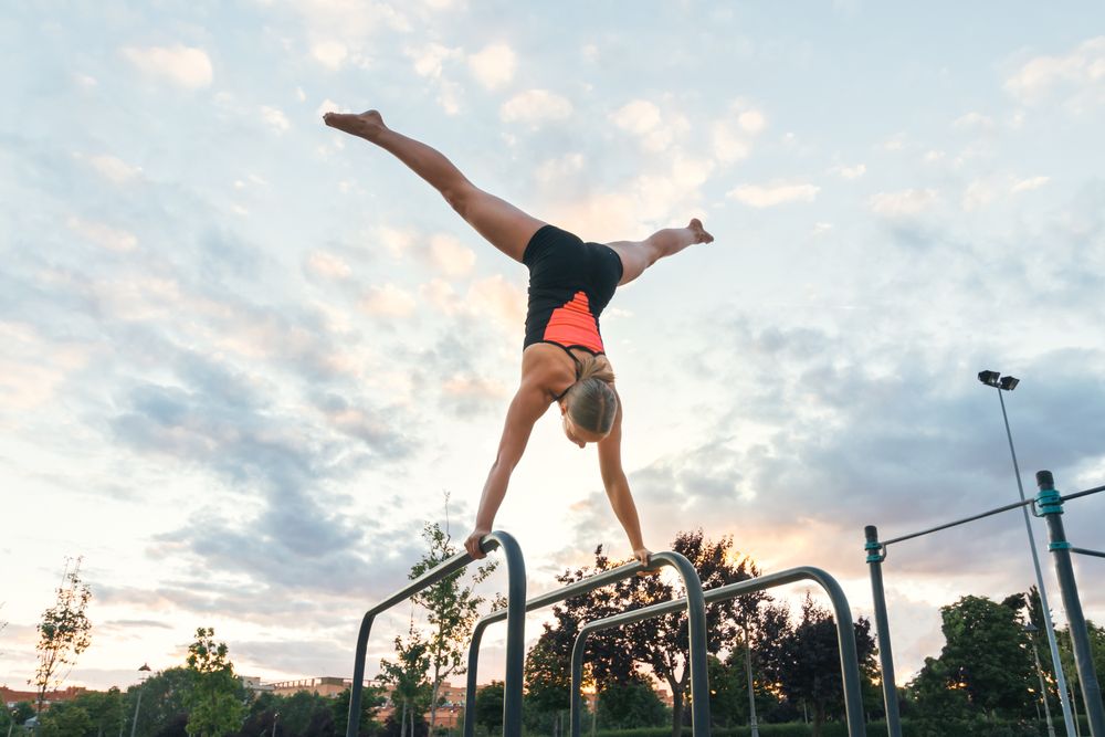 woman gymnast doing handstand on parallel bars