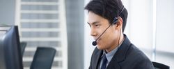 Side view of Asian man working at service desk talking on phone