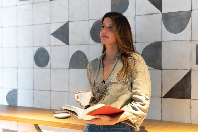 Dreamy woman with book and coffee in cafe