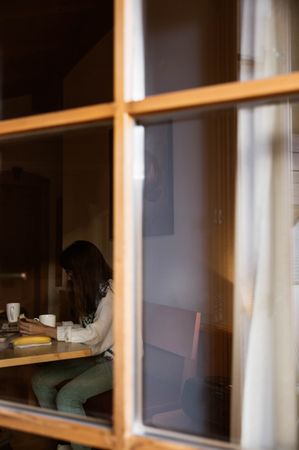 woman drinking of cup of hot beverage sitting at table