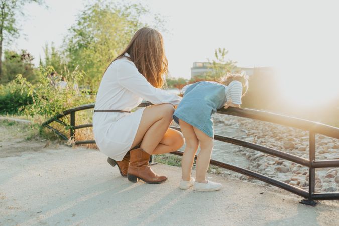 Anonymous mother and daughter looking at river in park