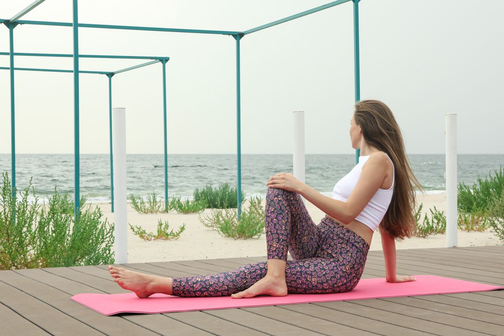 Woman on yoga mat on wooden floor outdoors