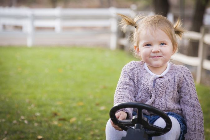 Young Toddler Smiling and Playing on Toy Tractor Outside