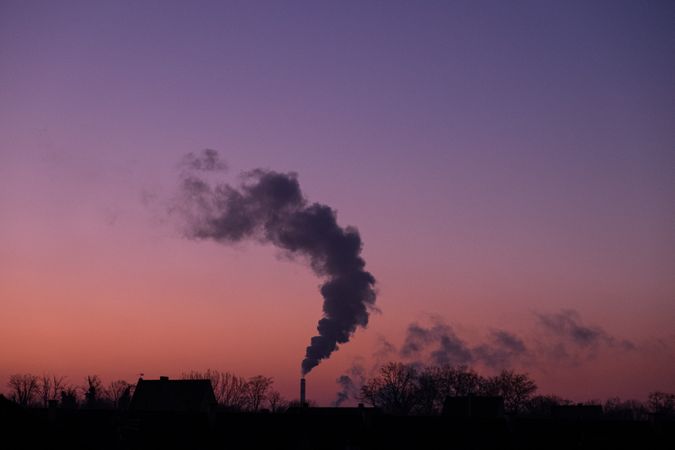 Smoke being released into pink purple morning sky