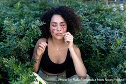 Beautiful young woman with afro hair surrounded by flowers with eyes closed 0ykea4