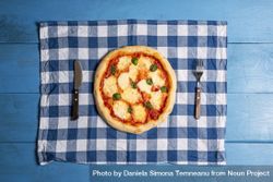 Overhead of whole margherita pizza on a blue table 0PEra5