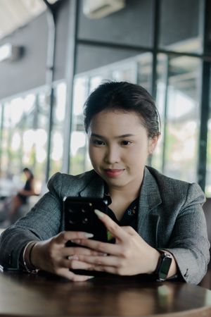 Professional Woman Engaging with Smartphone During Coffee Break
