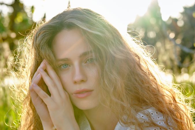 Woman touching face in sunny summer garden