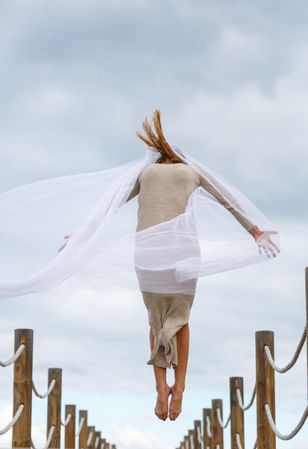 Woman with textile posing in air on footbridge