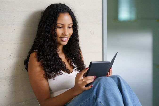 A Young Woman is Delightfully Enjoying a Digital Book on a Cozy and Relaxing Afternoon