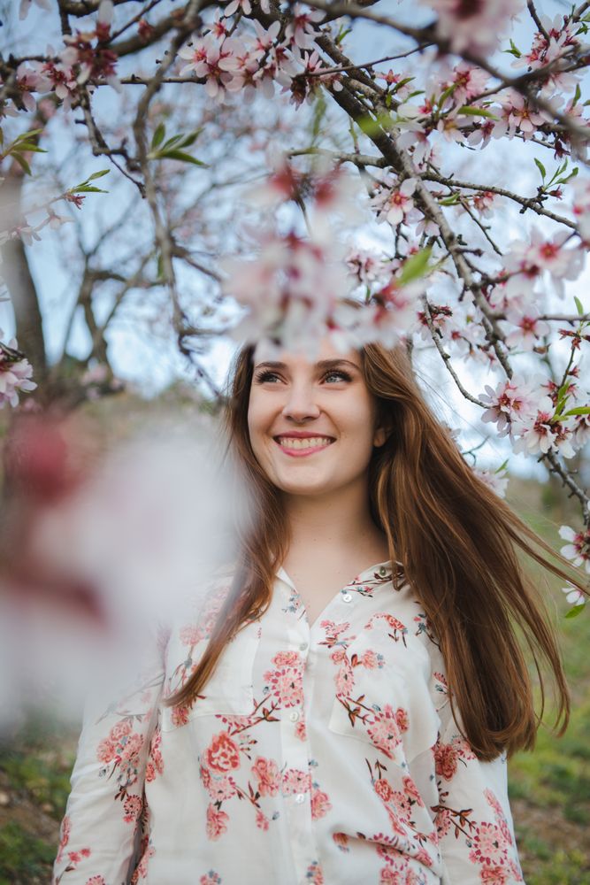 Young happy woman between trees in garden