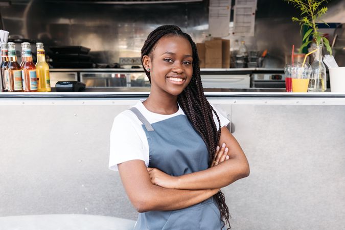Smiling Black woman in apron outside her silver food truck