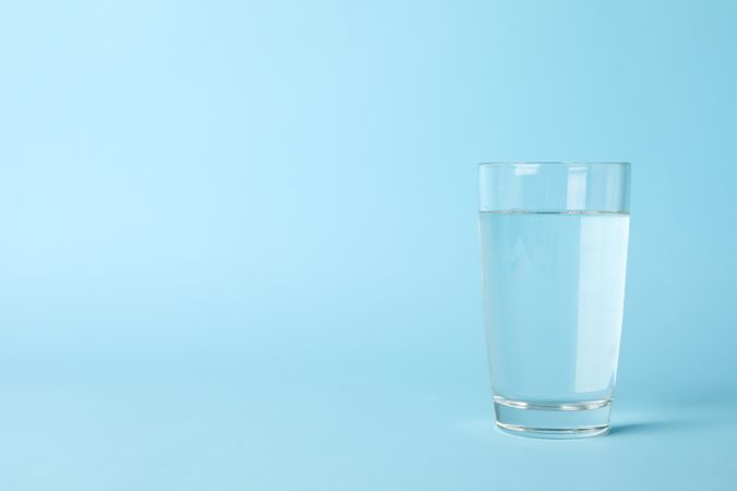 Full glass of water in light blue room