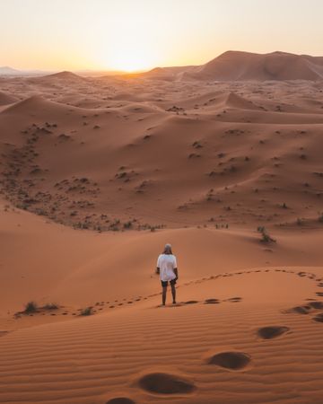 man in white summer t-shirt walking in desert