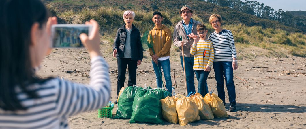 Girl taking photo to group of volunteers after cleaning beach