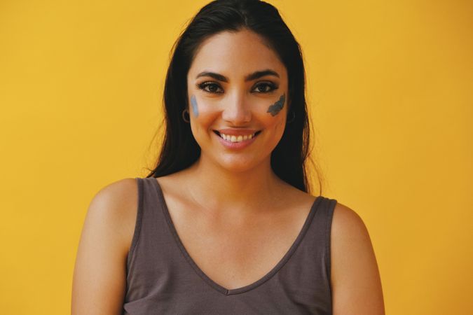 Happy Latina woman with clay mask on cheeks, copy space