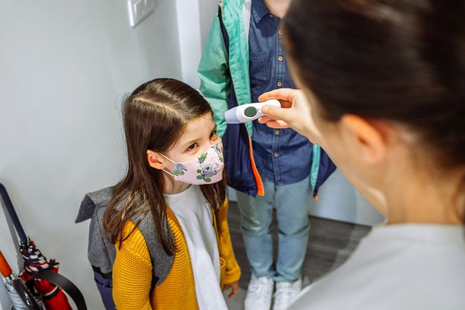 Mother checking her daughter's temperature before going to school
