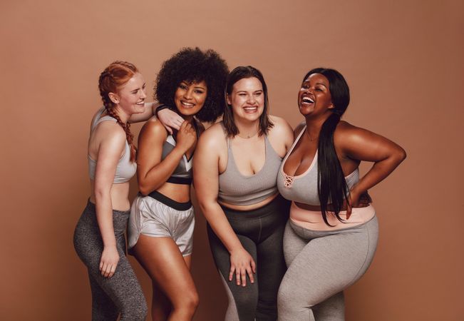 Diverse workout friends smiling against brown background
