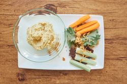 Tasty hummus with sliced vegetables on plate
