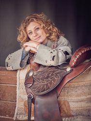 Delightful person with saddle in wooden stable