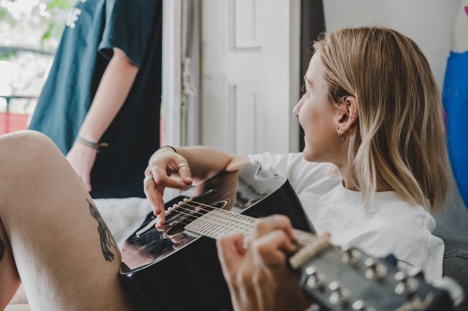 Lesbian couple playing guitar on bed