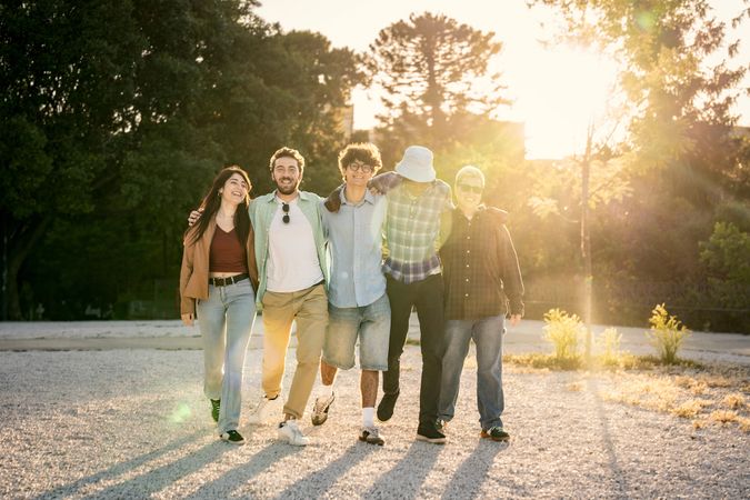 Diverse group of friends walking together on a path towards the sunset.