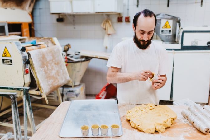 Bearded confectioner putting dough into cup