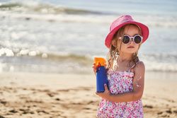 portrait of a girl with a bottle of sunscreen on the beach