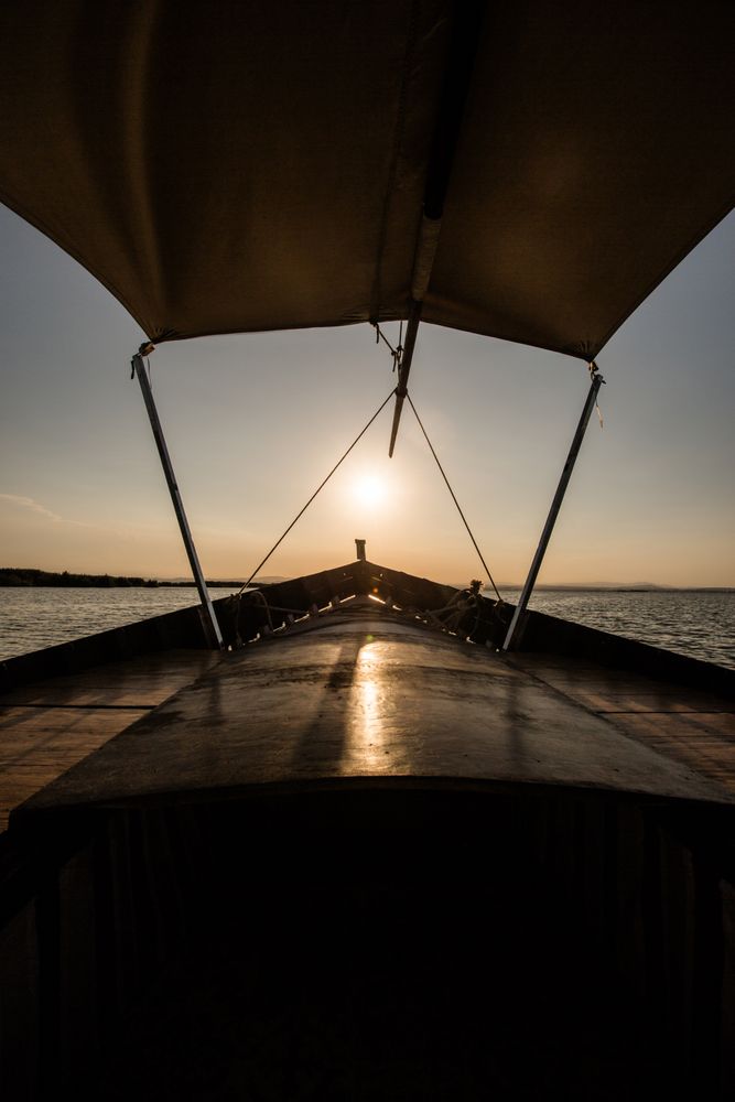 Front of boat riding along sea at twilight