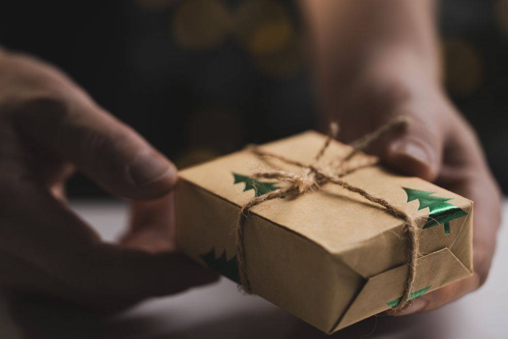 Man holding Christmas gift by wooden table