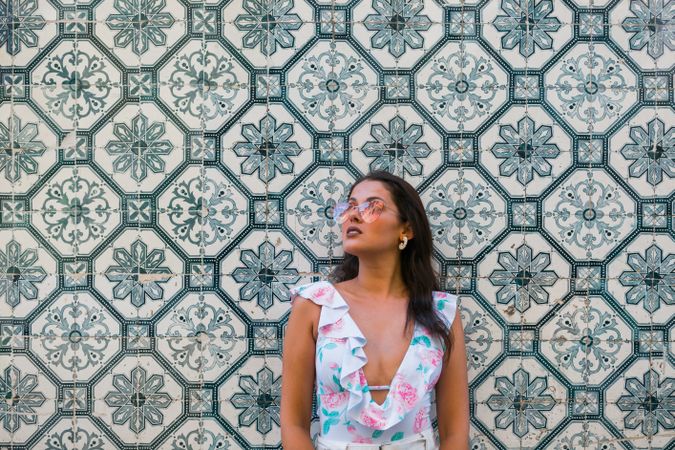 Dreamy stylish woman in sunglasses standing on city street