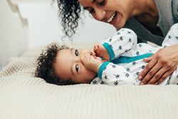 Baby boy lying down with smiling mother