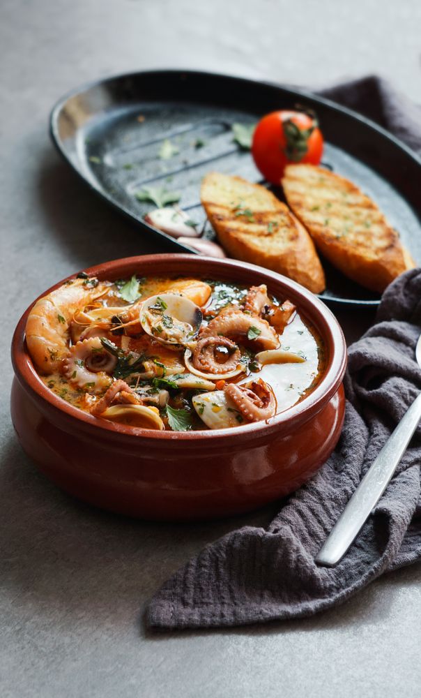 Soup of octopus and shrimps near toasts and spoon