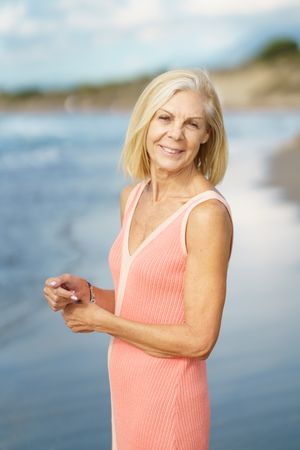 Vertical composition of calm smiling older woman standing near coast