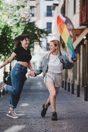 Lesbian couple with LGBT flag walking on street