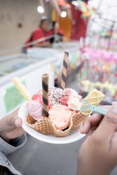 A young Hispanic woman is eating a traditional ice cream in front of a street market stall