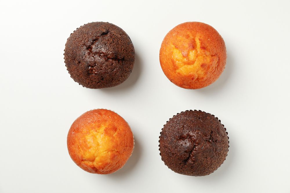 Flat lay with tasty muffins on light background, top view