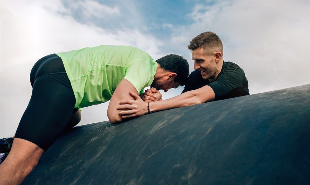 Men in an obstacle course climbing a drum